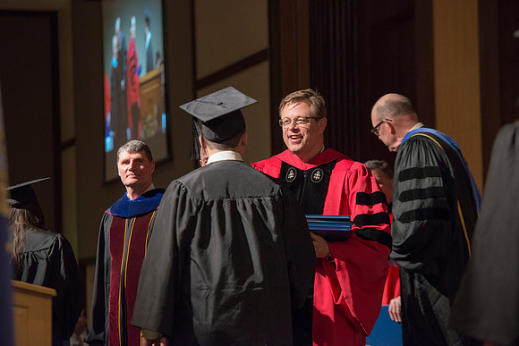 College of Language and Letters Convocation in the Manwaring Center Ballroom. Eric Walz, Pres Gilbert and Elder Clayton present the graduates with their diploma covers.