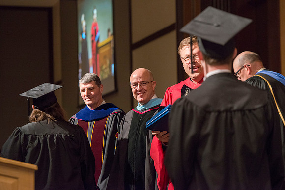 College of Language and Letters Convocation in the Manwaring Center Ballroom. Eric Walz, Pres Gilbert and Elder Clayton present the graduates with their diploma covers.