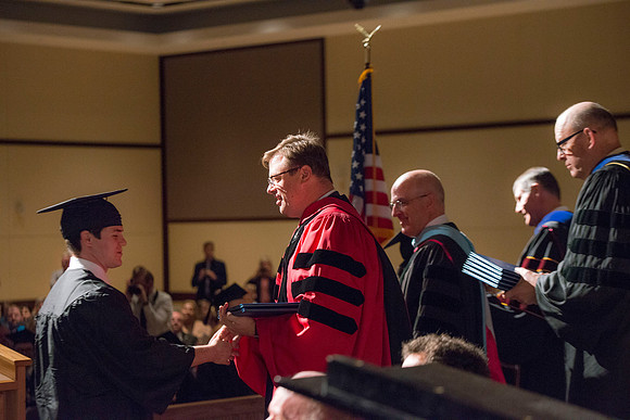 College of Language and Letters Convocation in the Manwaring Center Ballroom. Eric Walz, Pres Gilbert and Elder Clayton present the graduates with their diploma covers.