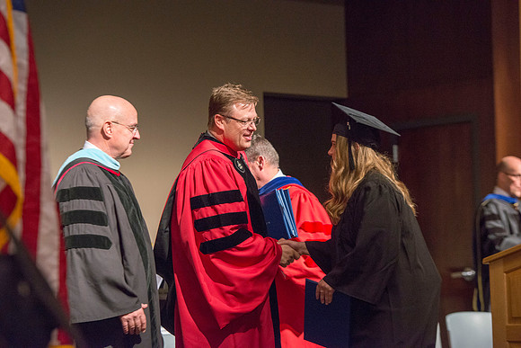College of Language and Letters Convocation in the Manwaring Center Ballroom. Eric Walz, Pres Gilbert and Elder Clayton present the graduates with their diploma covers.