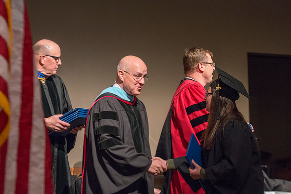 College of Language and Letters Convocation in the Manwaring Center Ballroom. Eric Walz, Pres Gilbert and Elder Clayton present the graduates with their diploma covers.