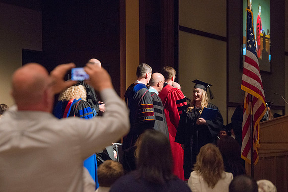 College of Language and Letters Convocation in the Manwaring Center Ballroom. Eric Walz, Pres Gilbert and Elder Clayton present the graduates with their diploma covers.