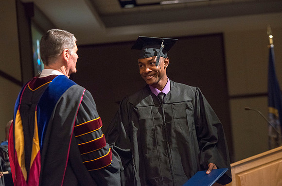 College of Language and Letters Convocation in the Manwaring Center Ballroom. Eric Walz congratulates a graduate.