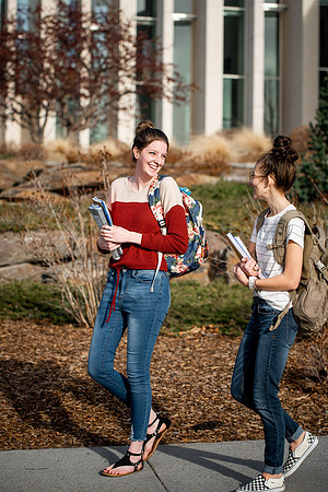 BYUI students Kira Wood and Abby Anderson walk around campus in front of the Taylor Building.