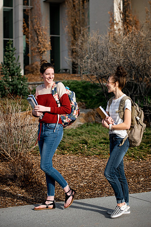 BYUI students Kira Wood and Abby Anderson walk around campus in front of the Taylor Building.