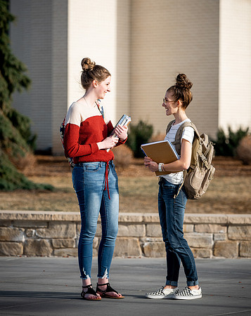 BYUI students Kira Wood and Abby Anderson walk around campus in front of the Taylor Building.