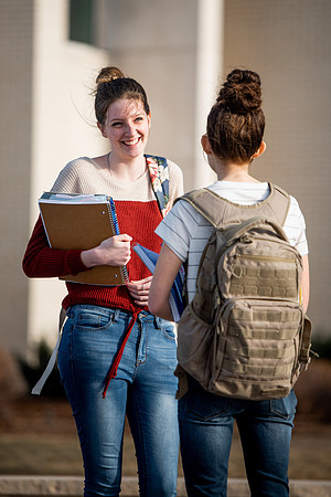 BYUI students Kira Wood and Abby Anderson walk around campus in front of the Taylor Building.