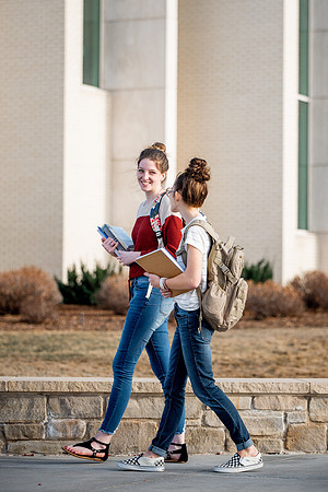 BYUI students Kira Wood and Abby Anderson walk around campus in front of the Taylor Building.