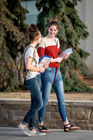 BYUI students Kira Wood and Abby Anderson walk around campus in front of the Taylor Building.