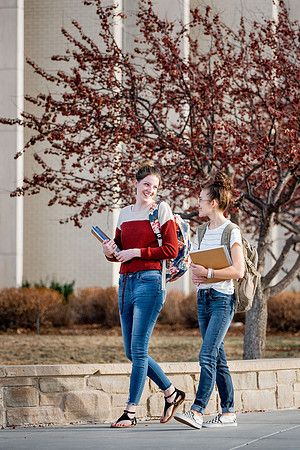 BYUI students Kira Wood and Abby Anderson walk around campus in front of the Taylor Building.