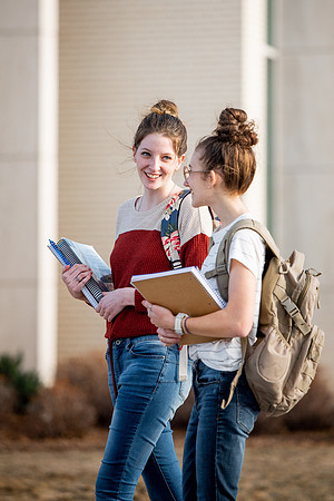 BYUI students Kira Wood and Abby Anderson walk around campus in front of the Taylor Building.