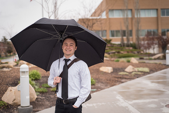 A student stands with an umbrella on campus. 2017