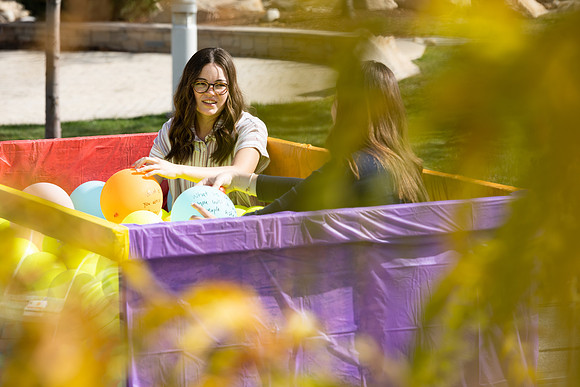Students who volunteer to participate sit in the ball pit and ask each other questions which are found on the balloons. Video is being produced for Student Living.