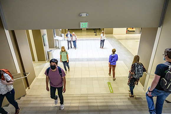 Student volunteers show the way to stay safe during this COVID 19 pandemic by social distancing, following pathway arrows and proper wearing of masks .