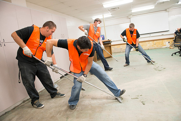Students hired by Servpro remove glue residue from the carpet removal.