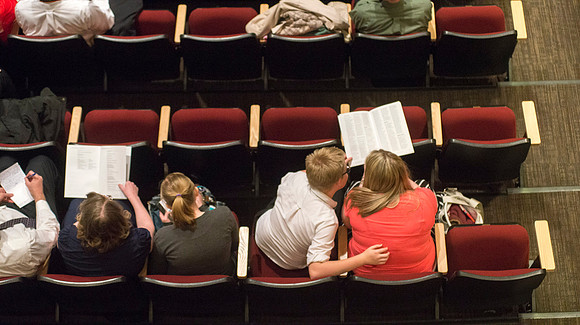 Members of the audience look at Commencement program.