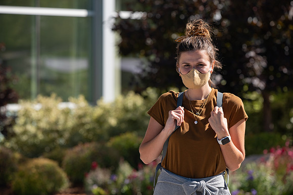 Examples of students staying safe and healthy during the COVID-19 pandemic by social distancing, following pathway arrows, and wearing face masks.
