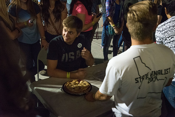 Students participate in a pie eating contest. Each pie is to be eaten by a team of three students who can only use their mouths to eat pies.