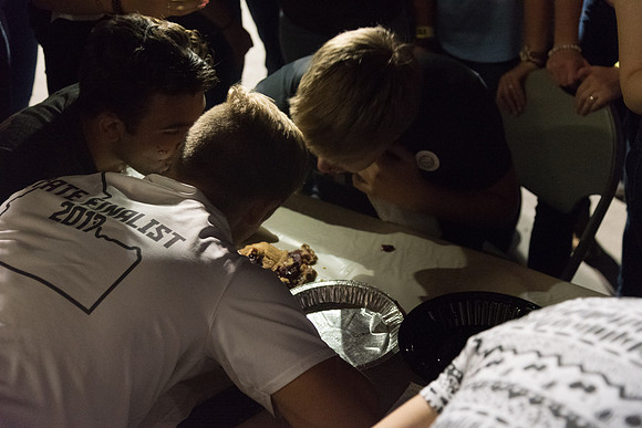 Students participate in a pie eating contest. Each pie is to be eaten by a team of three students who can only use their mouths to eat pies.