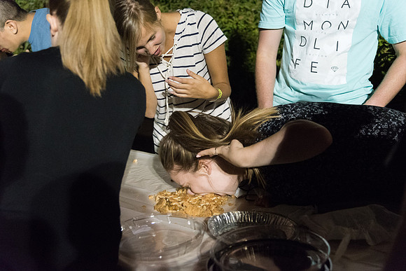 Students participate in a pie eating contest. Each pie is to be eaten by a team of three students who can only use their mouths to eat pies.