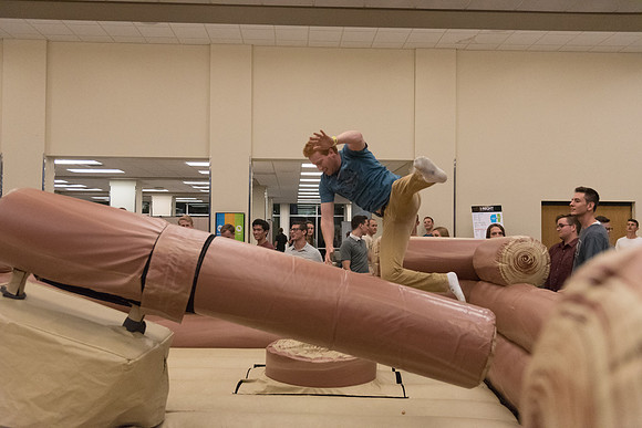 Students stand on inflatable platforms and try not to get knocked over by a spinning arm. They must jump and duck.
