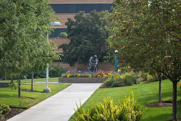 The sidewalk in the Smith quad leads to the statue of students studying.