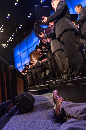 University Photographer, Garrett Blanchard, hides down behind the barrier while the choir performs at the Inauguration.