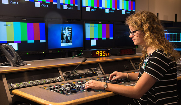 McKenzie Marcum sitting at the controls in the camera control room in the BYU-Idaho Center.