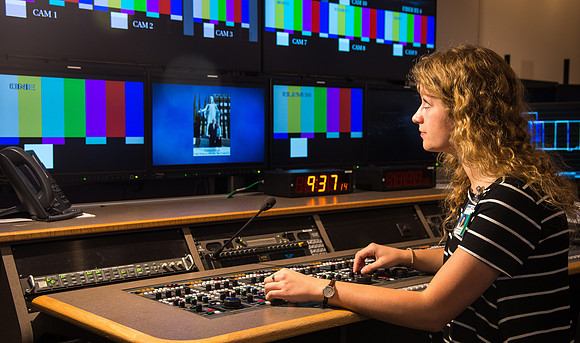 McKenzie Marcum sitting at the controls in the camera control room in the BYU-Idaho Center.