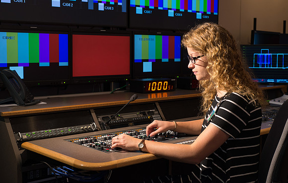 McKenzie Marcum sitting at the controls in the camera control room in the BYU-Idaho Center.