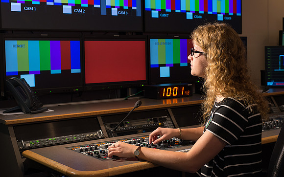 McKenzie Marcum sitting at the controls in the camera control room in the BYU-Idaho Center.