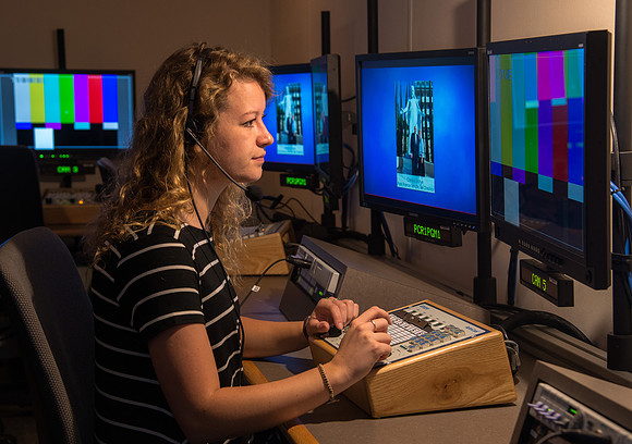 McKenzie Marcum sitting at the controls in the camera control room in the BYU-Idaho Center.