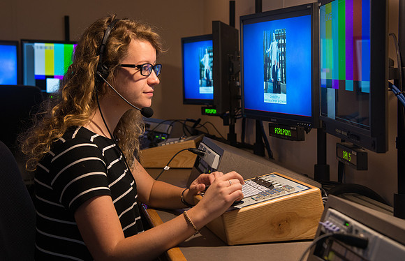McKenzie Marcum sitting at the controls in the camera control room in the BYU-Idaho Center.
