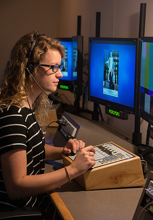 McKenzie Marcum sitting at the controls in the camera control room in the BYU-Idaho Center.