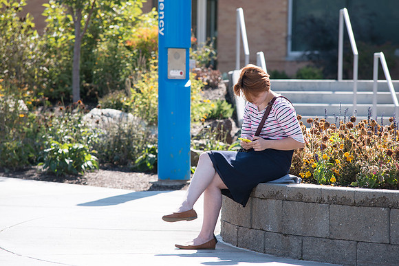 A student passes time between classes outside the MC Building, on the first day of school.