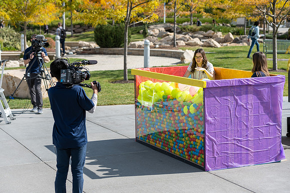 Students who volunteer to participate sit in the ball pit and ask each other questions which are found on the balloons. Video is being produced for Student Living.