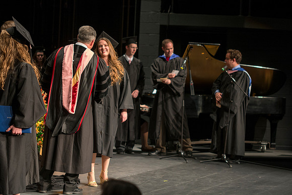 Faculty members hand degrees to and congratualate graduates of the College of Performing and Visual Arts.
