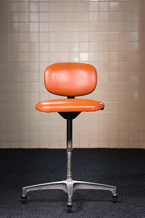 A lone orange chair sits in the hallway.