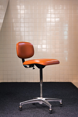 A lone orange chair sits in the hallway.