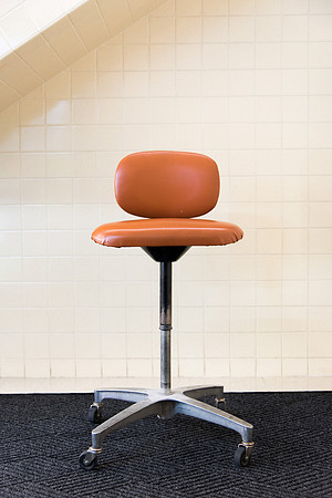 A lone orange chair sits in the hallway.