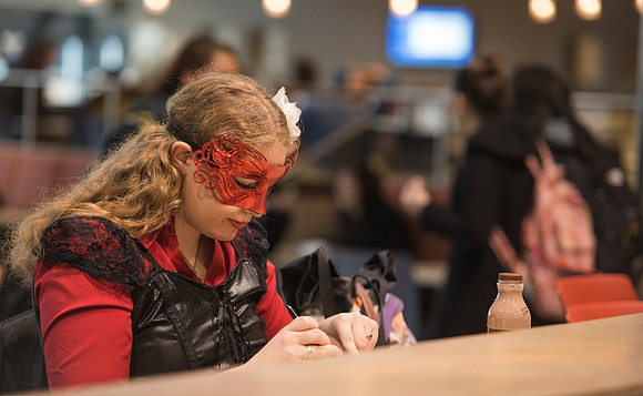 A student, dressed up for Halloween, eats lunch in the Manwaring Center