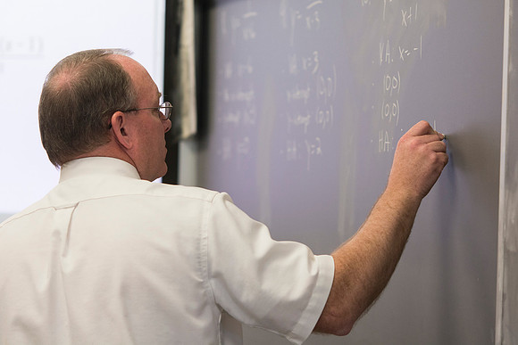 Brother Johanson writes a problem on the chalkboard for his Math 109 Precalculus to solve during the 2014 Spring Semester.