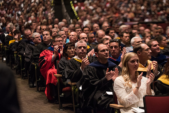 Professors and Faculty applaud the graduates for their accomplishments.