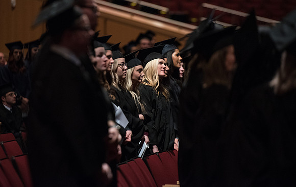 Graduates stand as they are recognized for their accomplishments.