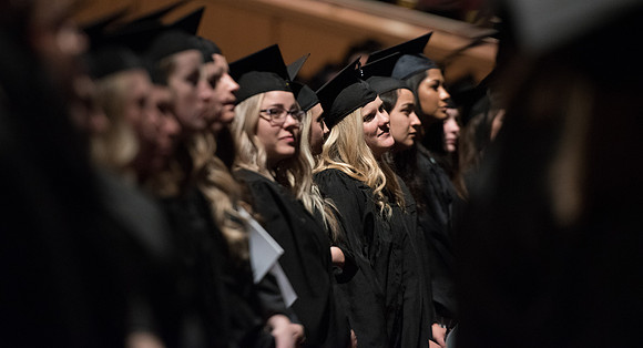 Graduates stand as they are recognized for their accomplishments.