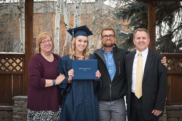 A graduate stand with her family in the gardens for a photo. 2017