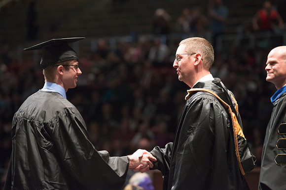 Convocation for College of Physical Sciences and Engineering in the Hart Auditorium.  Graduates receive their diploma covers.