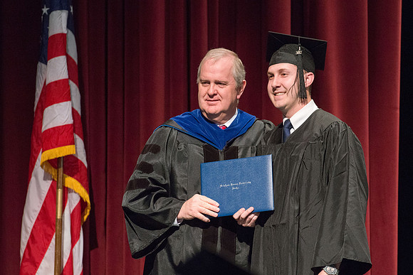 Convocation for College of Physical Sciences and Engineering in the Hart Auditorium.  Graduates receive their diploma covers.