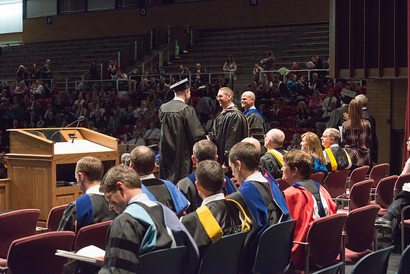 Convocation for College of Physical Sciences and Engineering in the Hart Auditorium.  Graduates receive their diploma covers.
