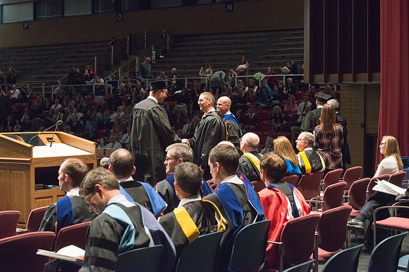 Convocation for College of Physical Sciences and Engineering in the Hart Auditorium.  Graduates receive their diploma covers.